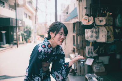 Portrait of smiling young woman standing in city