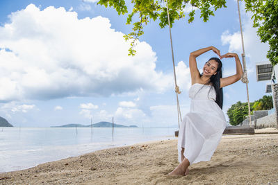 Beautiful woman sitting on a swing at the beach in phuket