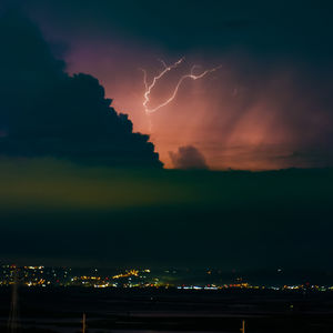 Lightning over illuminated cityscape at night