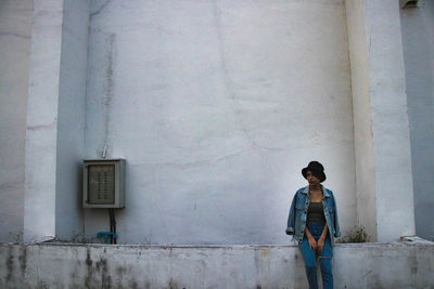 Full length of woman standing against building wall