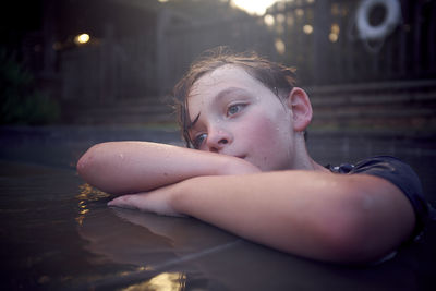 Close-up of thoughtful boy looking away while standing at poolside