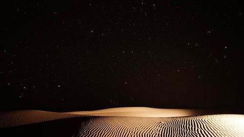 Scenic view of desert against star field at night