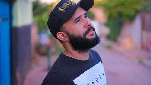 Close-up of thoughtful bearded man wearing cap looking away outdoors