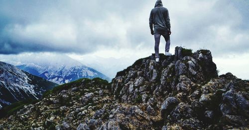 Rear view of man standing on rock against sky