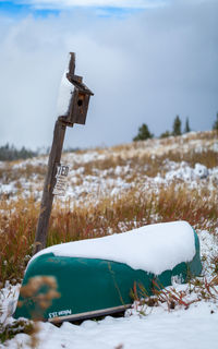 Abandoned birdhouse by boat on snow covered field