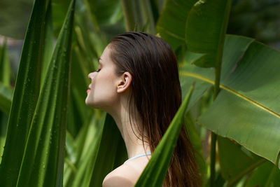 Side view of woman standing against tree