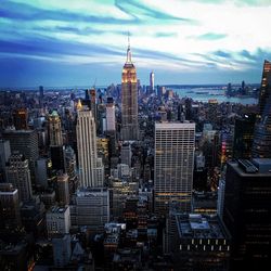 Aerial view of buildings in city against cloudy sky