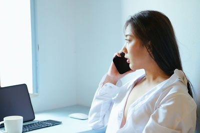 Woman using phone while sitting on table