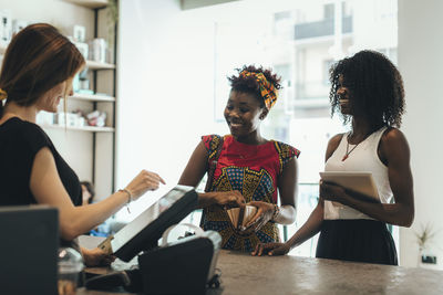 Two customers paying at counter in a coffee bar