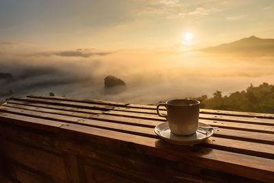 Close-up of cup on table during sunrise