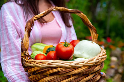 Midsection of woman holding vegetables in basket. smells like freshly picked vegetables