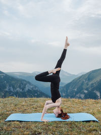 Full length of woman climbing on mountain against sky