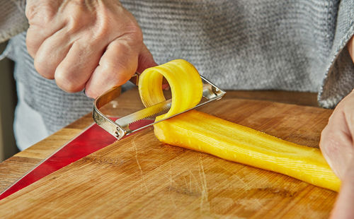 Chef cuts slices of carrots of three colors in the kitchen on wooden board