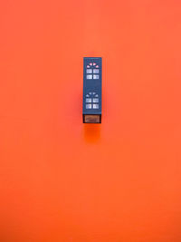 Close-up of telephone booth against orange wall