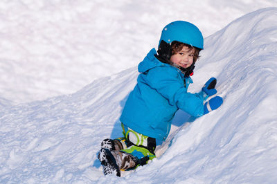 Portrait of smiling boy playing on snow covered mountain