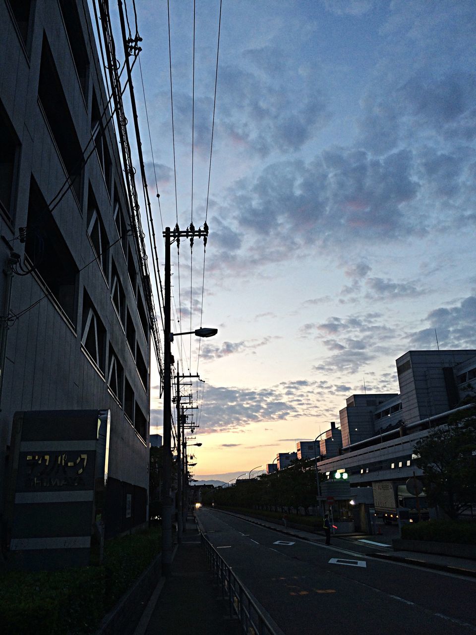 building exterior, sky, transportation, architecture, built structure, city, road, cloud - sky, street, sunset, the way forward, car, road marking, mode of transport, cloud, land vehicle, cloudy, street light, diminishing perspective, dusk