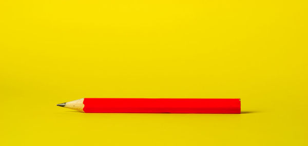 Close-up of red pencils against yellow background