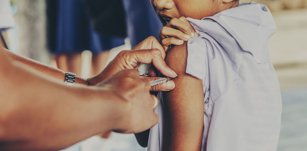 Cropped image of doctor injecting syringe to boy