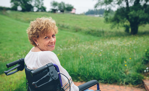Portrait of smiling senior woman sitting on wheelchair at park