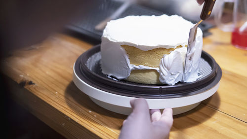 Close-up of hand holding chocolate cake on table