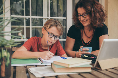 Teacher teaching boy while sitting at home