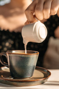 Cropped hand of woman holding coffee on table