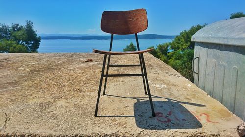 Old chair on landscape against clear sky