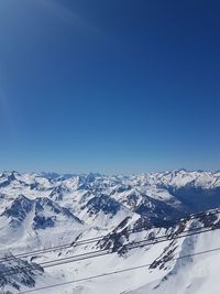 Scenic view of snowcapped mountains against clear blue sky