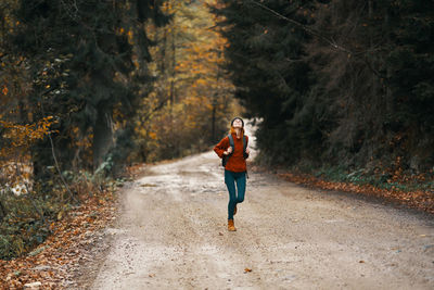 Full length of man running on road in forest