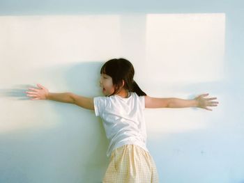 Portrait of young woman standing against wall