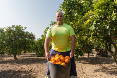 Farmer showing a basket with oranges.