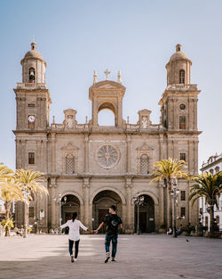 People in front of historic building against clear sky