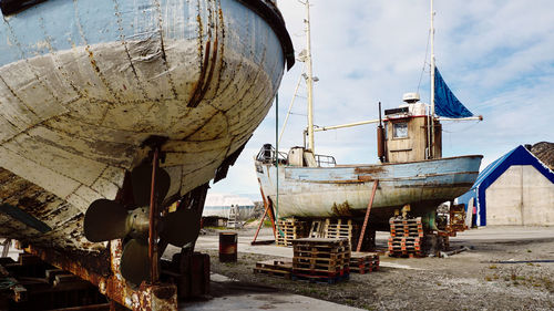 Abandoned boat moored at shore against sky