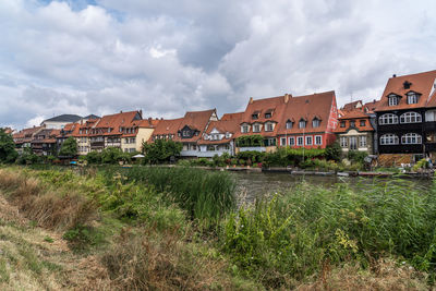 Buildings by houses against sky in city