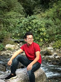 Portrait of a smiling young man sitting on rock