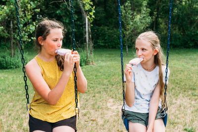 Side view of young woman sitting on swing at playground