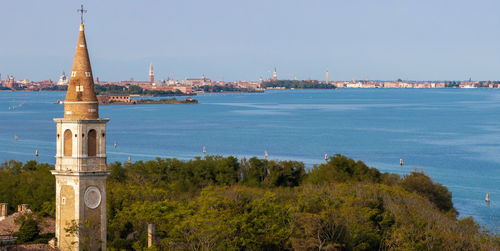 Buildings by sea against clear sky