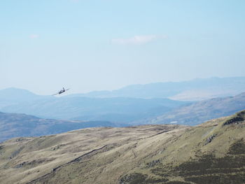 Fighter plane flying over mountain against sky