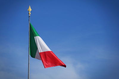 Low angle view of flag against blue sky