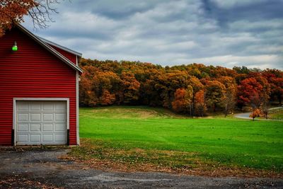 House on field by trees against sky