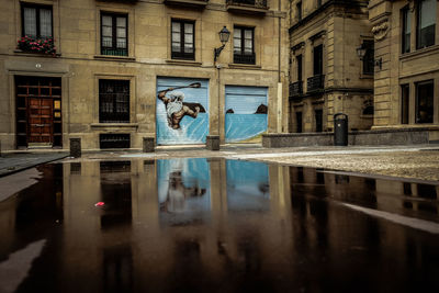 Reflection of buildings on wet street in city