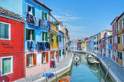 Boats moored in canal amidst buildings against sky