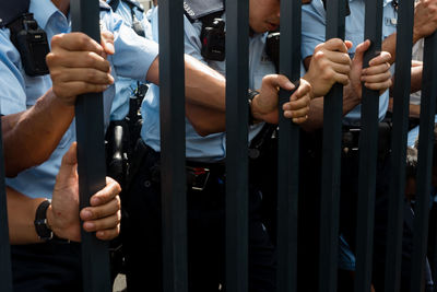 Midsection of police holding gate while standing outdoor