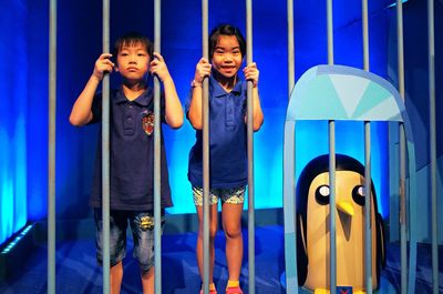 Portrait of boys standing against blue wall