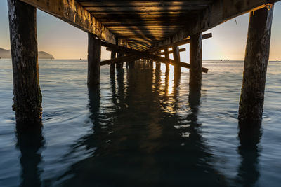 Pier on sea against sky during sunset