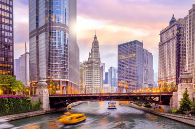 Bridge over river by buildings against sky in city