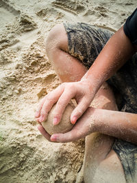 High angle view of hands on sand at beach