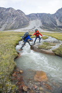 Backpackers help one another cross a river in akshayak pass.