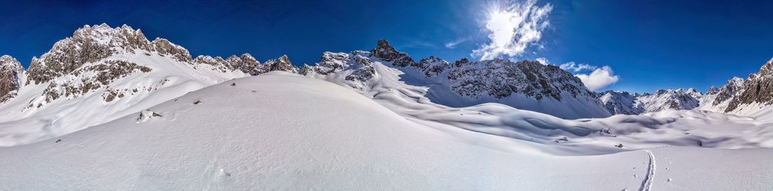 Panoramic view of snow covered mountains against sky