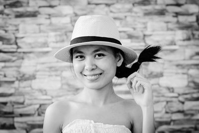 Close-up portrait of happy young woman wearing hat while standing against wall